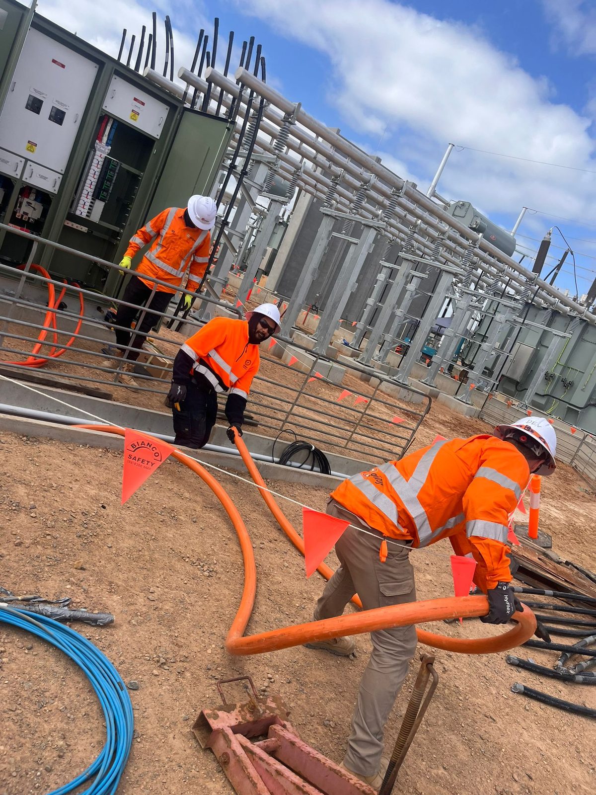 Four of the crew feeding orange conduit through the switchyard