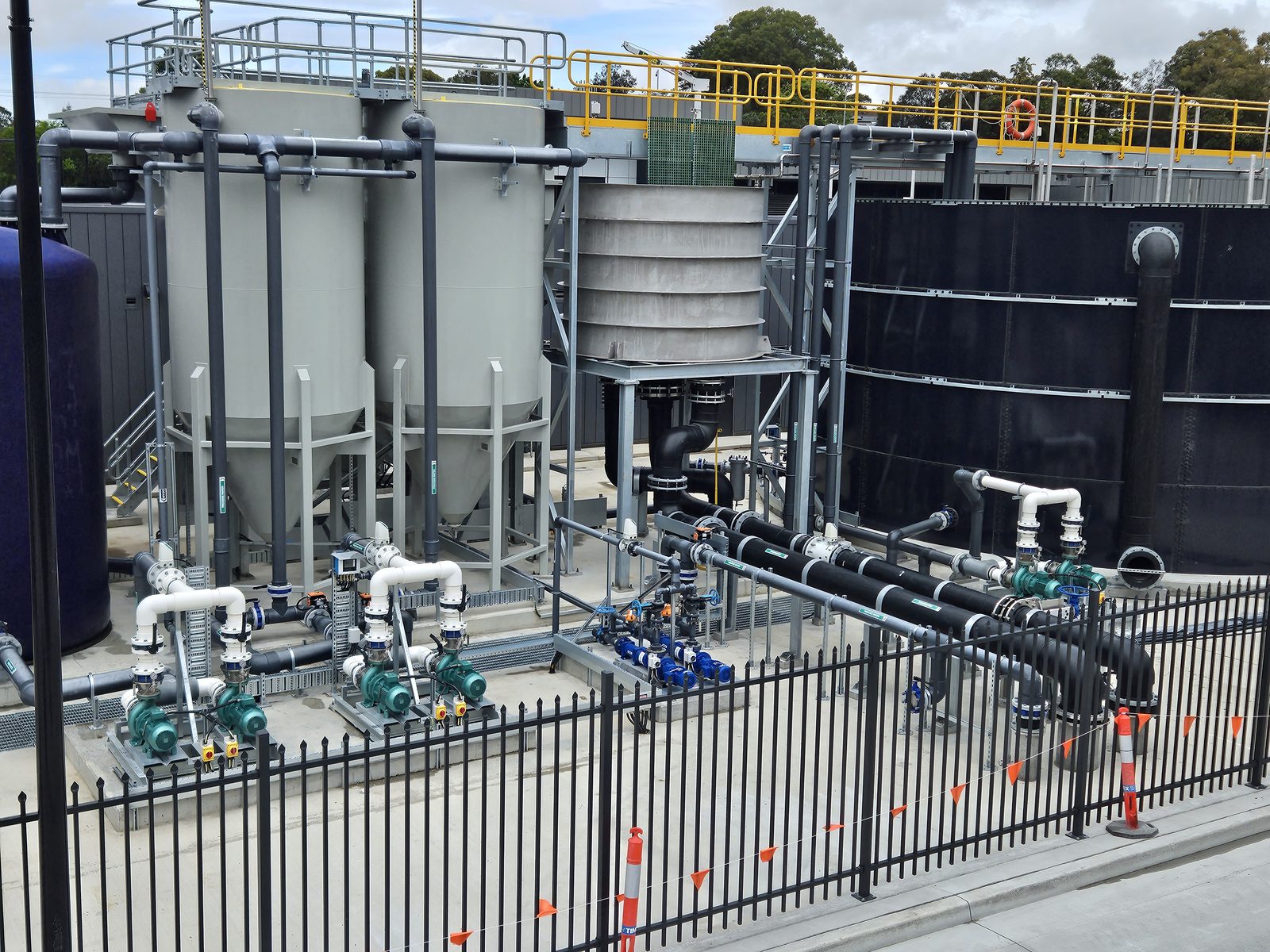 Wide site overview of the Rozelle water treatment plant area — tanks, clarifier and pump skids under a bright sky; clean