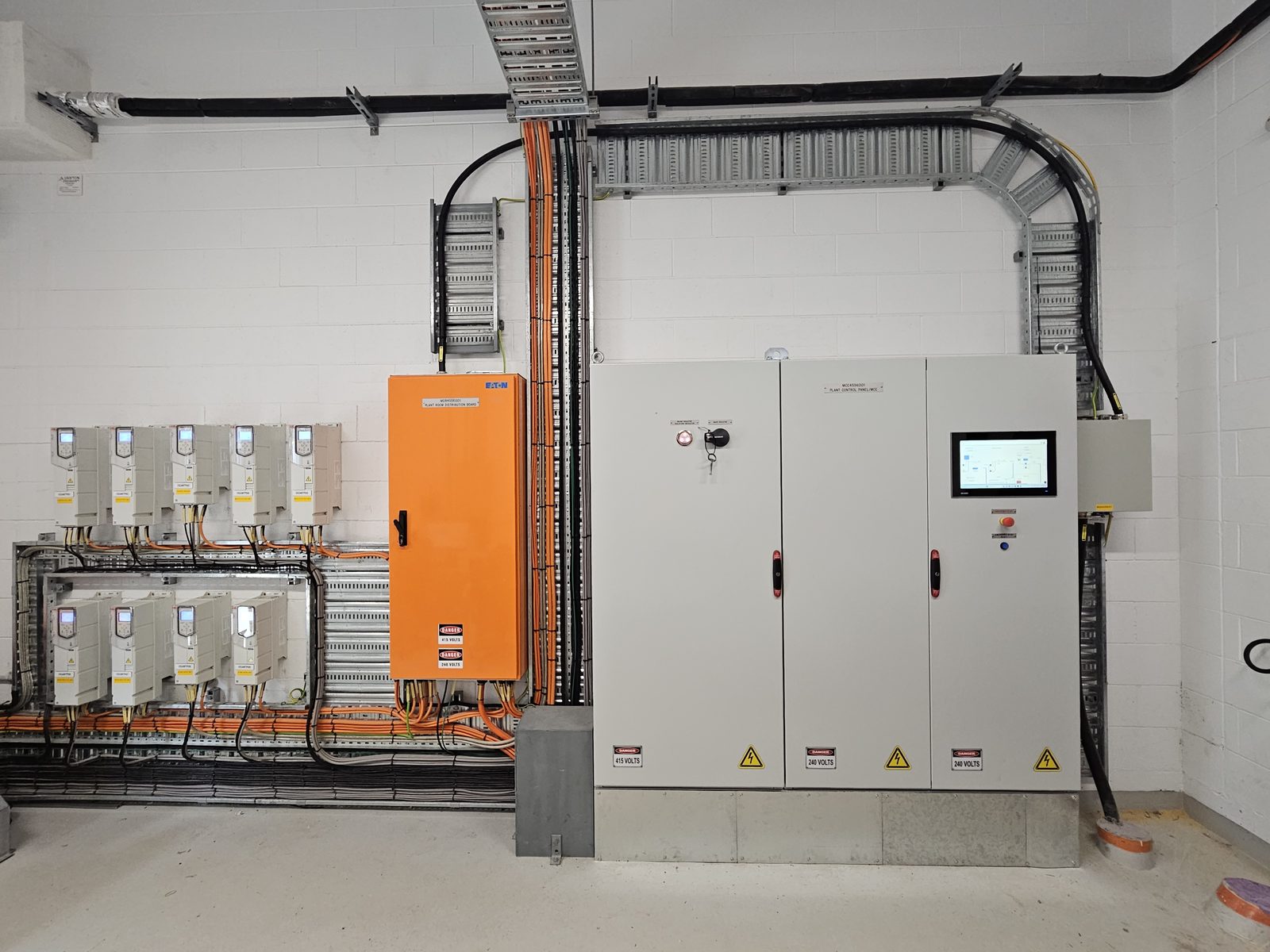Finished switchroom: MCC/plant control panels, orange distribution board, VSD wall and immaculate cable tray runs — stro